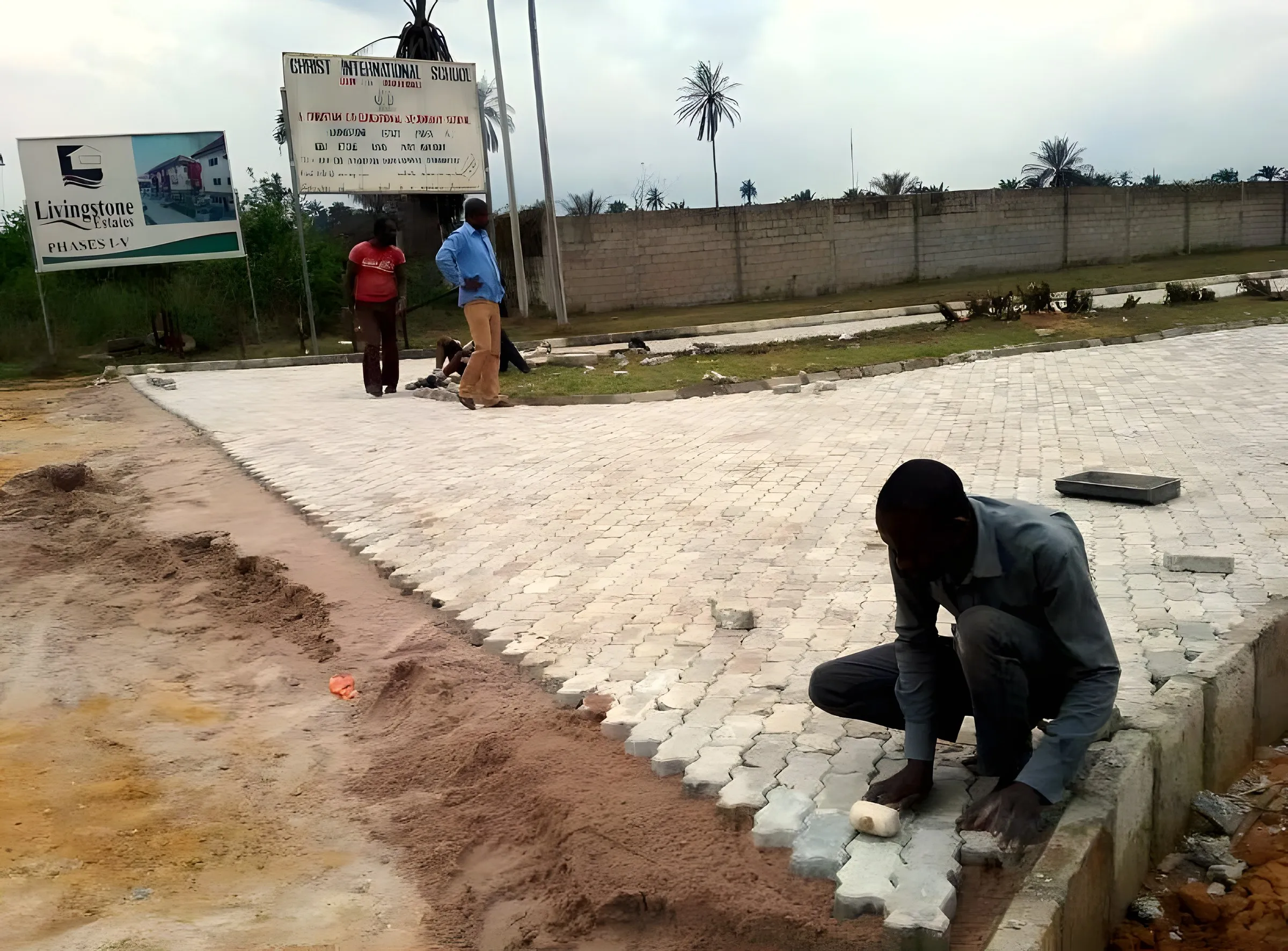 Worker laying interlocking paving stones by the estate sign